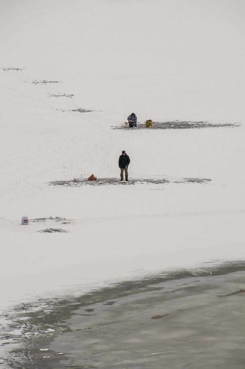 Two people fishing on a snowy ice surface