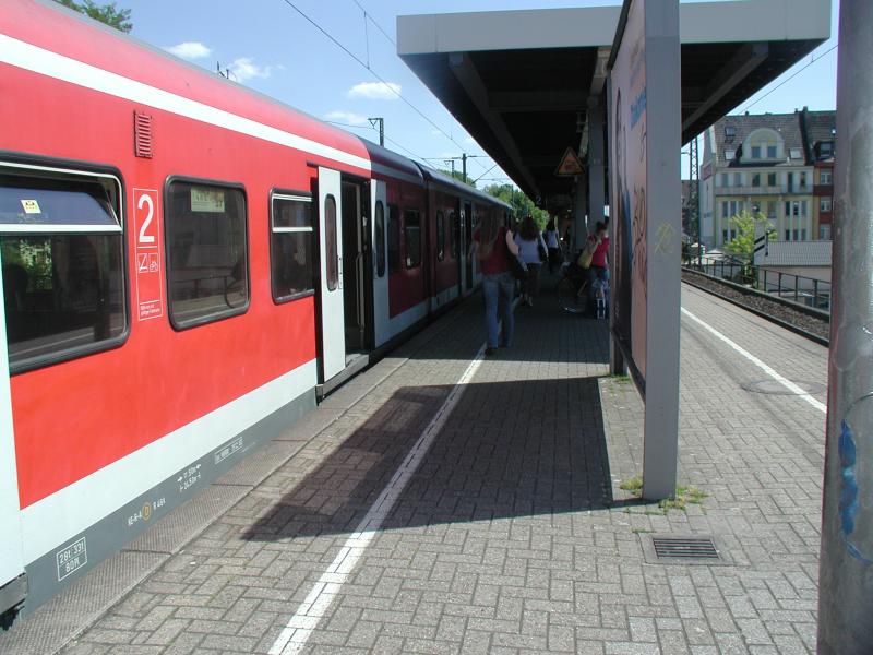 Red regional train on platform with passengers