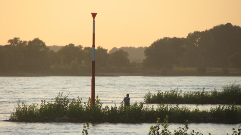 Angler with rod on a river in the evening light
