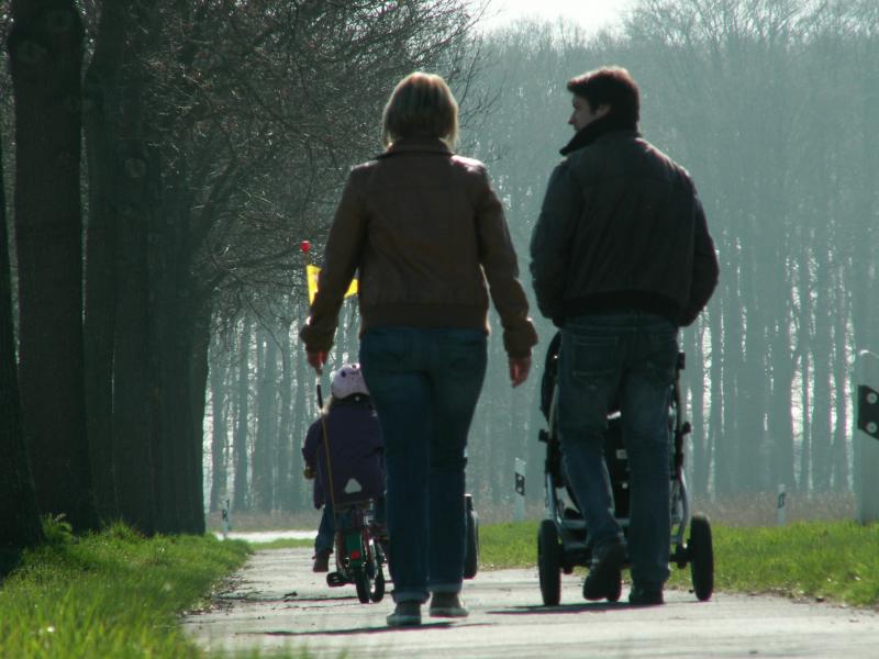 Family with stroller and child on a forest path