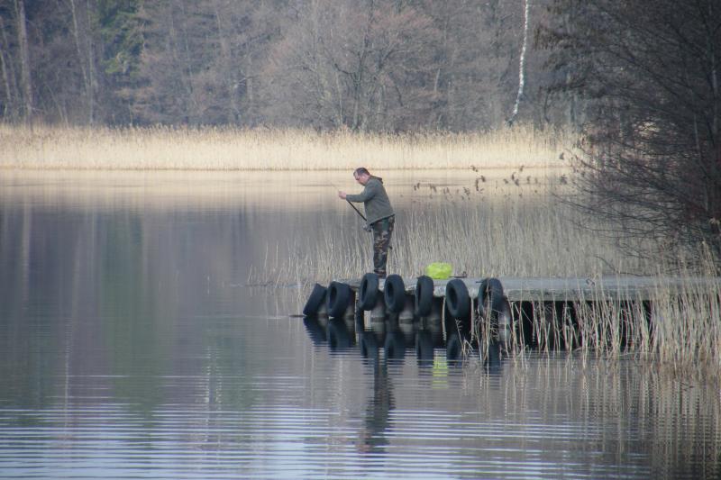 Angler on a jetty on a quiet lake with reeds