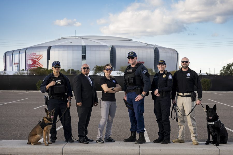 State Farm Stadium in Glendale, Arizona, with people standing in front of the stadium