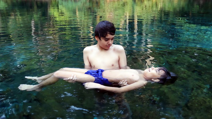 Two people swimming in a calm river surrounded by dense vegetation in Las Estacas near Tlaltizapán.
