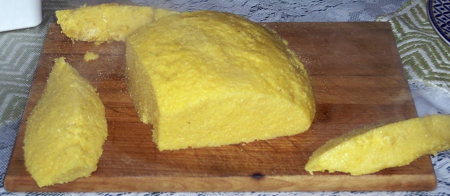 Served Mămăligă, a firm Romanian cornmeal dish, on a plate.