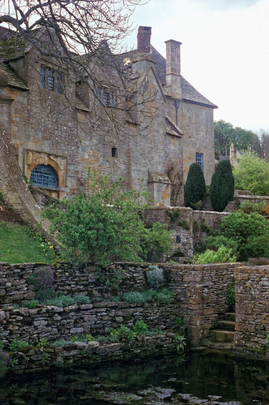 Priest's House von Snowshill Manor hinter einem Zierteich und terrassierten Garten