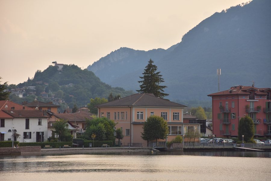 Promenade along the shore of Porto Ceresio on Lake Lugano with a view of the surrounding hills