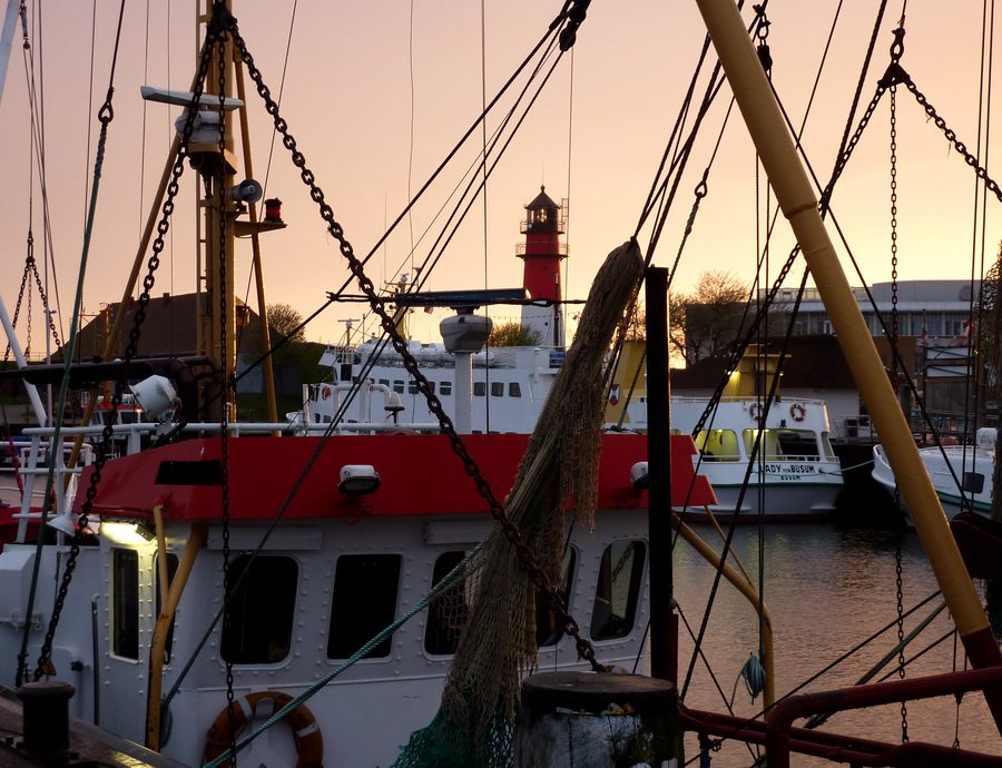 Harbor of Büsum with boats and lighthouse at sunset