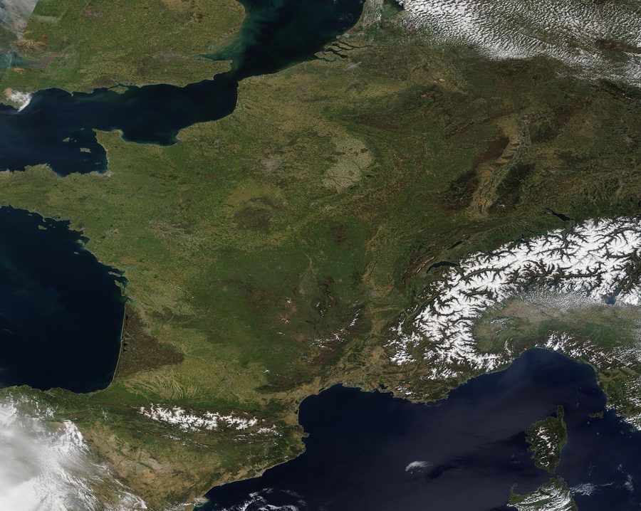 Satellite image of Western Europe with bright sunshine and some cloud formations.