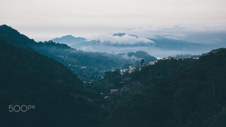 View of La Trinidad with houses and green hills in Southeast Asia.
