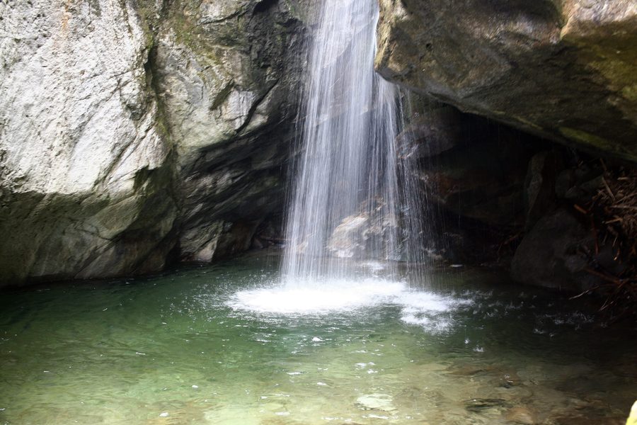 Kostenets Waterfall cascading through a wooded mountain setting.