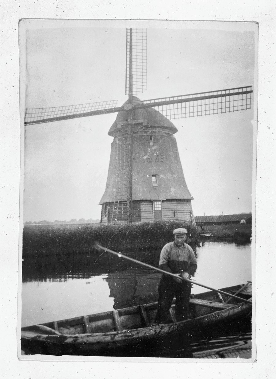 A man in a rowing boat in front of Molen D of the Geestmerambacht polder near Broek op Langedijk
