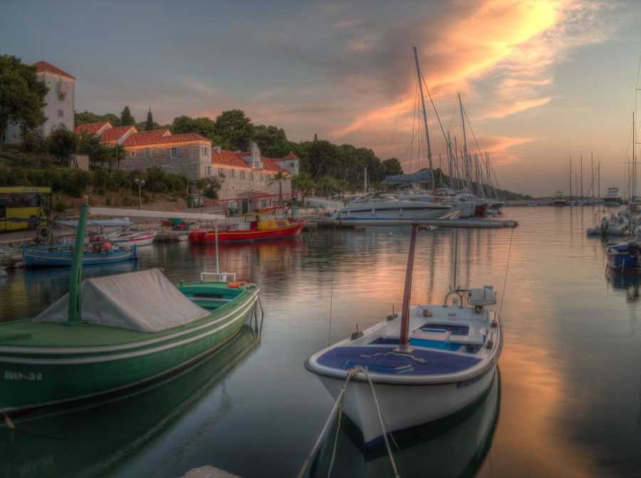 Harbor of Maslinica on the island of Šolta at sunset with a fishing boat and coastal landscape