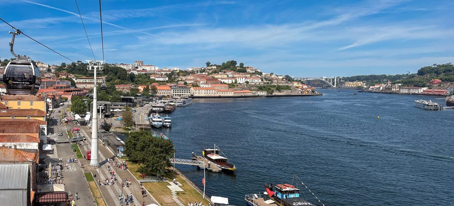 Blick auf das Douro-Ufer von Vila Nova de Gaia mit Seilbahn, Flussbooten und Porto im Hintergrund