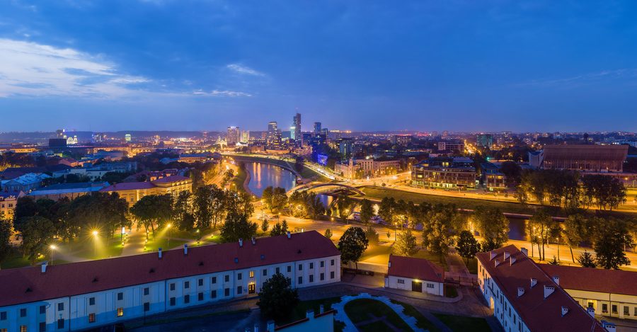 Skyline of Vilnius at dusk with illuminated buildings.