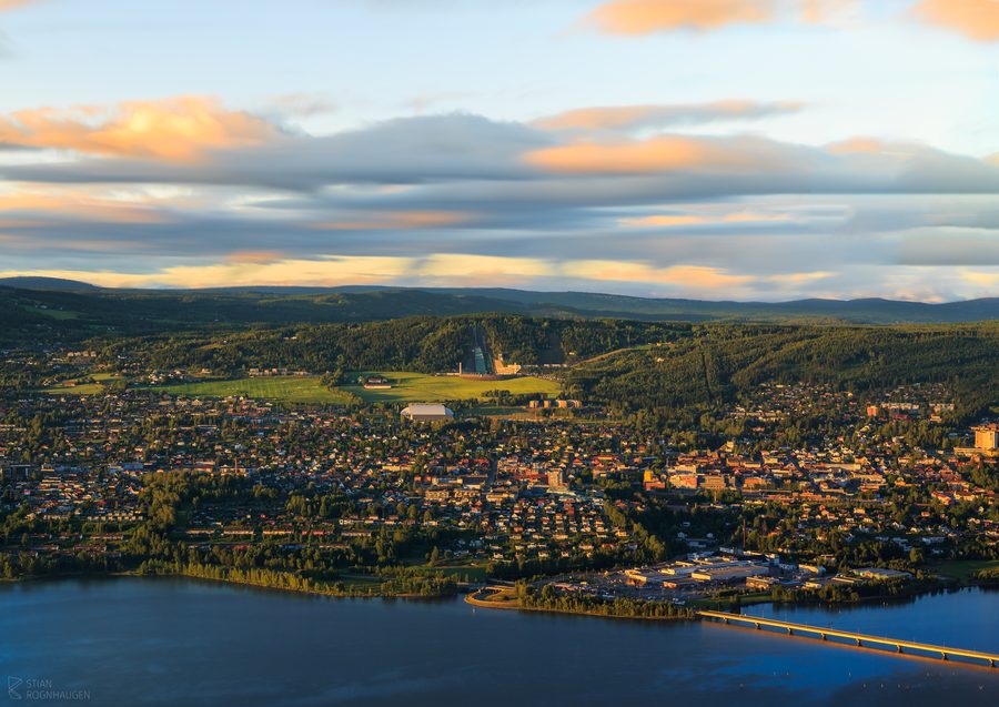 A view over Lillehammer with buildings clustered along the valley and surrounding hills.