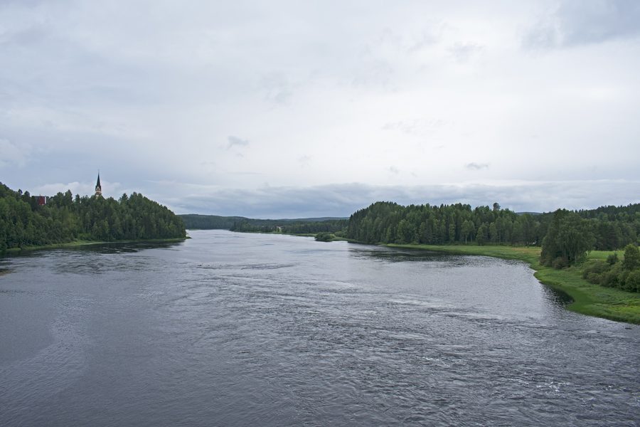 The Vindel River at Vindeln, seen from a bridge downstream, surrounded by forested landscape