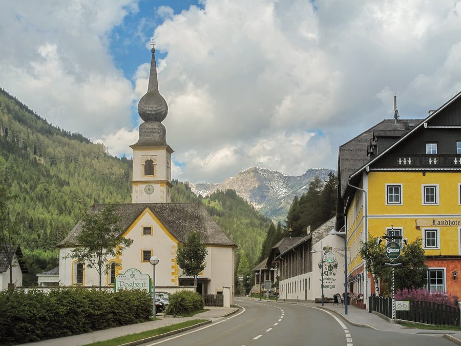 Pfarrkirche von Tweng im Straßenbild vor alpiner Bergkulisse